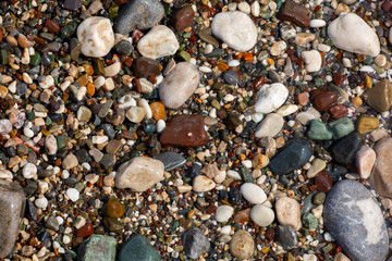 Stones texture. Background the damp multi-colored pebbles close up soft focus from on the pebbly beach in cloudy weather.