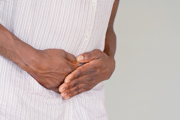 Elderly african man holding his stomach in pain isolated on gray background.