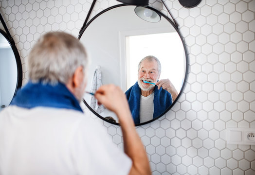 A Senior Man Brushing Teeth In Bathroom Indoors At Home. Copy Space.