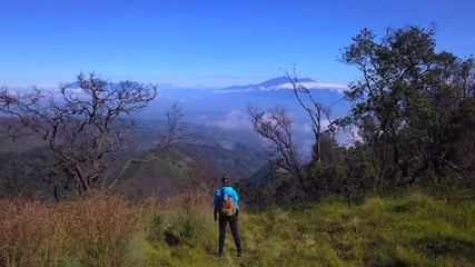 Woman rising hands on the mountain area of Java island, Indonesia, drone shot