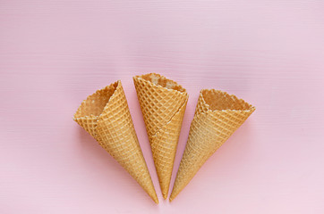 Three empty waffle cones on a pink background. Minimalism. Flat lay.