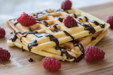 Two Viennese waffles with chocolate and berries on a wooden Board