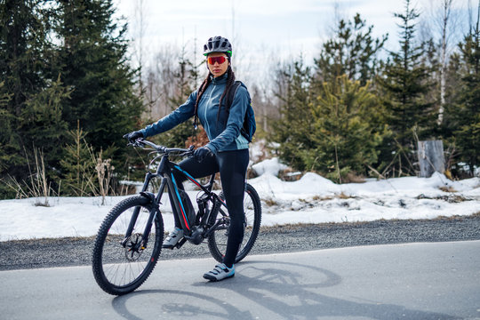 Female mountain biker standing on road outdoors in winter nature.