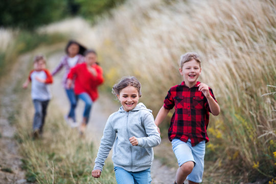 Group of school children running on field trip in nature.