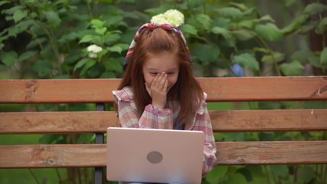 shocked and smiling child using laptop in park