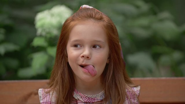 adorable child grimacing with flowers in park
