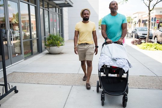 Men walking on road with baby stroller