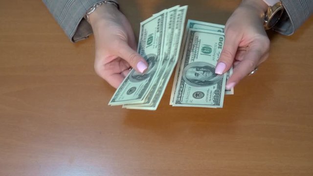Close-up, female hands are holding one hundred dollar bills. To count money. 700 dollars.