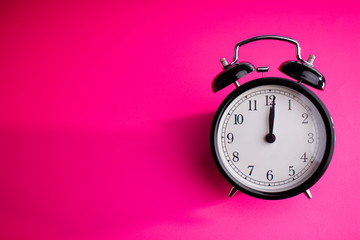 Clock on a pink background with a shadow on the left