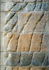 A stone wall with embossed stripes on a stone lit by the sun