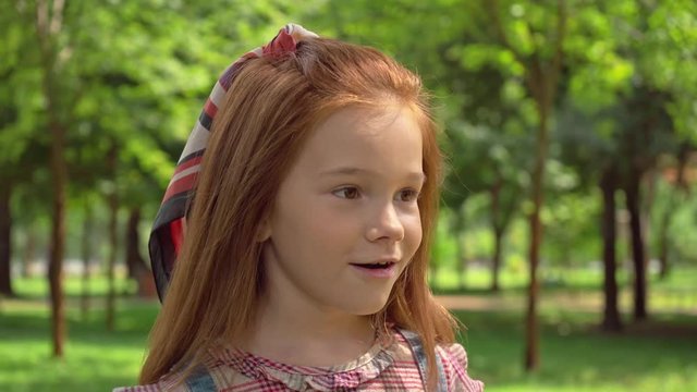 cute redhead child walking in green sunny park