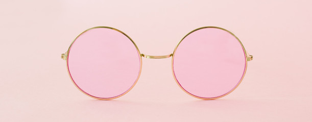 Round hipster sunglasses with pink lenses and golden frame. Fashion accessory for women