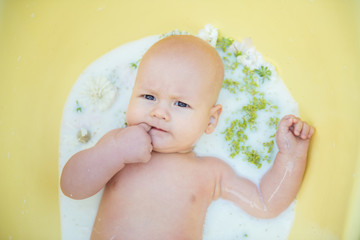 Close up of a baby in milk bath with natural flowers