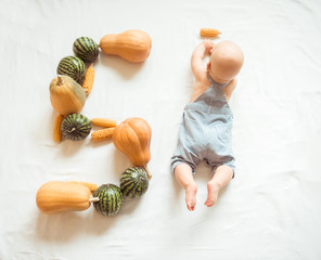 The cute baby is five months old. Figure 5 of pumpkin, corn and watermelon. Autumn, harvest, natural concept