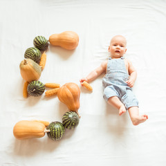 The cute baby is five months old. Figure 5 of pumpkin, corn and watermelon. Autumn, harvest, natural concept