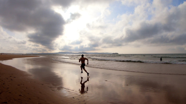 Athlete silhouette of runner running on beach
