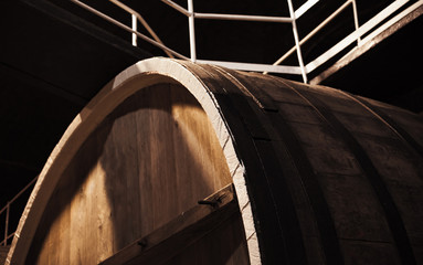 Old brown wooden barrel in dark winery