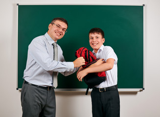 Portrait of a teacher and schoolboy playing at blackboard background - back to school and education concept