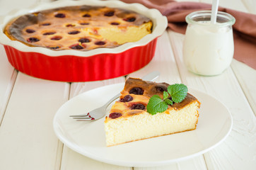 Diet healthy cottage cheese cake with cherries and sour cream on a white wooden background.