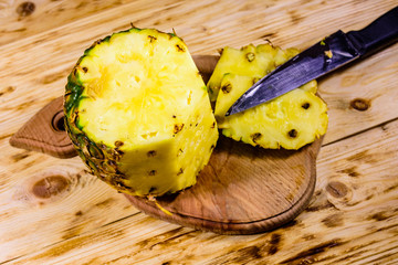 Cutting board with halved pineapple on wooden table