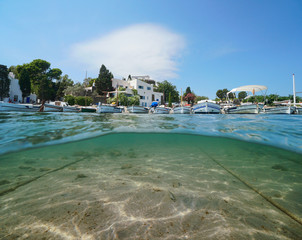 Spain Cadaques, typical boats on the sea shore and sand underwater, Portlligat village, Costa Brava, Catalonia, Mediterranean sea, split view above and below water surface