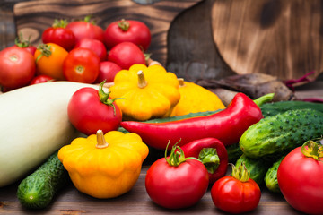 Fresh vegetables - squash, cucumbers, tomatoes, zucchini, peppers on a wooden table