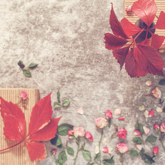 Red leaves are on a small wooden box. Nearby are scattered small dried roses. Autumn composition. Flat lay.