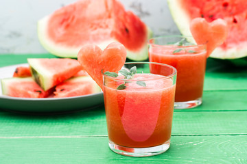 Fresh watermelon blended drink with mint leaves and a heart of watermelon in glasses on a wooden table