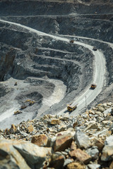Top view, open pit work. Large quarry dump trucks take out rock on the winding road