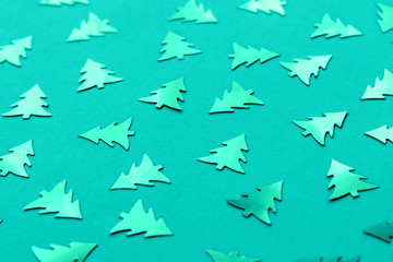 Metallic Christmas trees on a trendy mint green background. Bright turquoise new year's concept. Shiny decorative elements pattern.