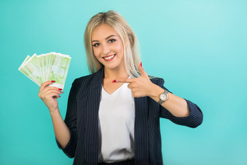 beautiful young woman in a black suit on a blue background with euro in hands