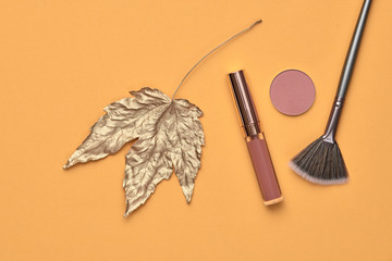 Fashion cosmetic makeup autumn Set. Minimal. Beauty product on orange background. Trendy accessories Brushes Eyeshadow art fashionable Flat lay. Creative make up fall autumnal concept
