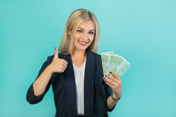 beautiful young woman in a black suit on a blue background with euro in hands