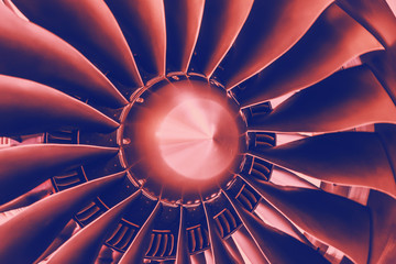 Close up of a turbofan turbine blades jet engine in modern airplane with pink and blue gradient...