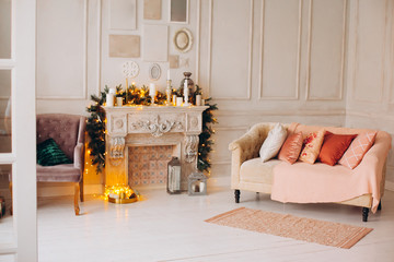 classical interior of a white room with a decorated fireplace, luxury Christmas tree, garlands, candles, lanterns, gifts. day. pink sofa pastel colors