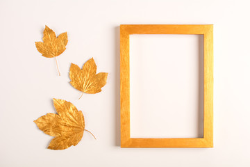 Naklejka na ściany i meble Autumn composition. Golden leaves and photo frame on a light background. Top view. Copy space