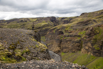 Fototapeta na wymiar Landmannalaugar, Iceland »; August 2017: A young man on a cliff on the Landmannalaugar trekking