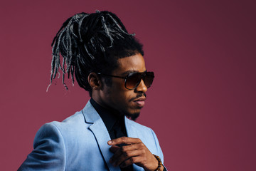 Profile portrait of a man with cool hair and sunglasses, against studio background