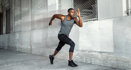 African american male athlete sprinter, running at a high speed in urban concrete city background...