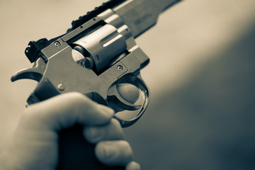 in one hand is large silver heavy revolver and aims into the air