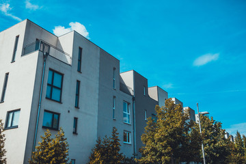 white and grey colored townhouses with green trees in the foreground