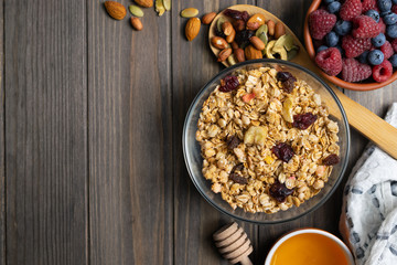 Healthy homemade granola with nuts, honey and berries in a glass bowl. Overhead flat lay