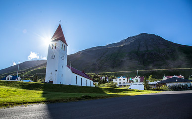 Siglufjordur, Iceland &raquo;; August 2017: The beautiful local church of the picturesque town called Siglufjordur with the sun in the background