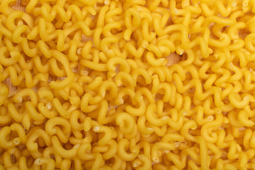 Raw yellow cavatappi pasta texture background top view