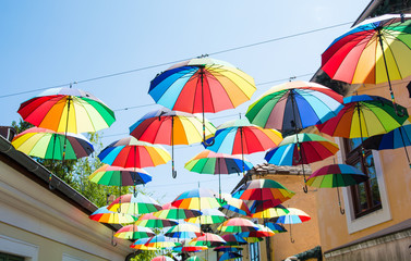 Rainbow umbrellas hanging above a street.