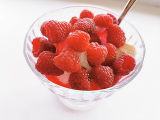 Ice cream in a glass creamer with fresh red raspberries. Summer dessert. Close-up photo