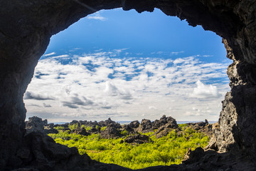Looking at the landscape and its clouds through the hole of a cave in Lake Myvatn, Iceland