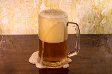 glass of beer with foam serving through the edges of the glass