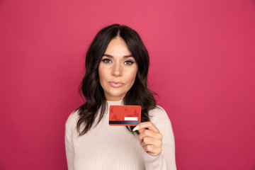 Happy woman with credit card isolated in the pink studio