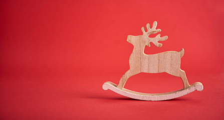 Christmas background. Cristmas decoration toy wooden deer over red background.
